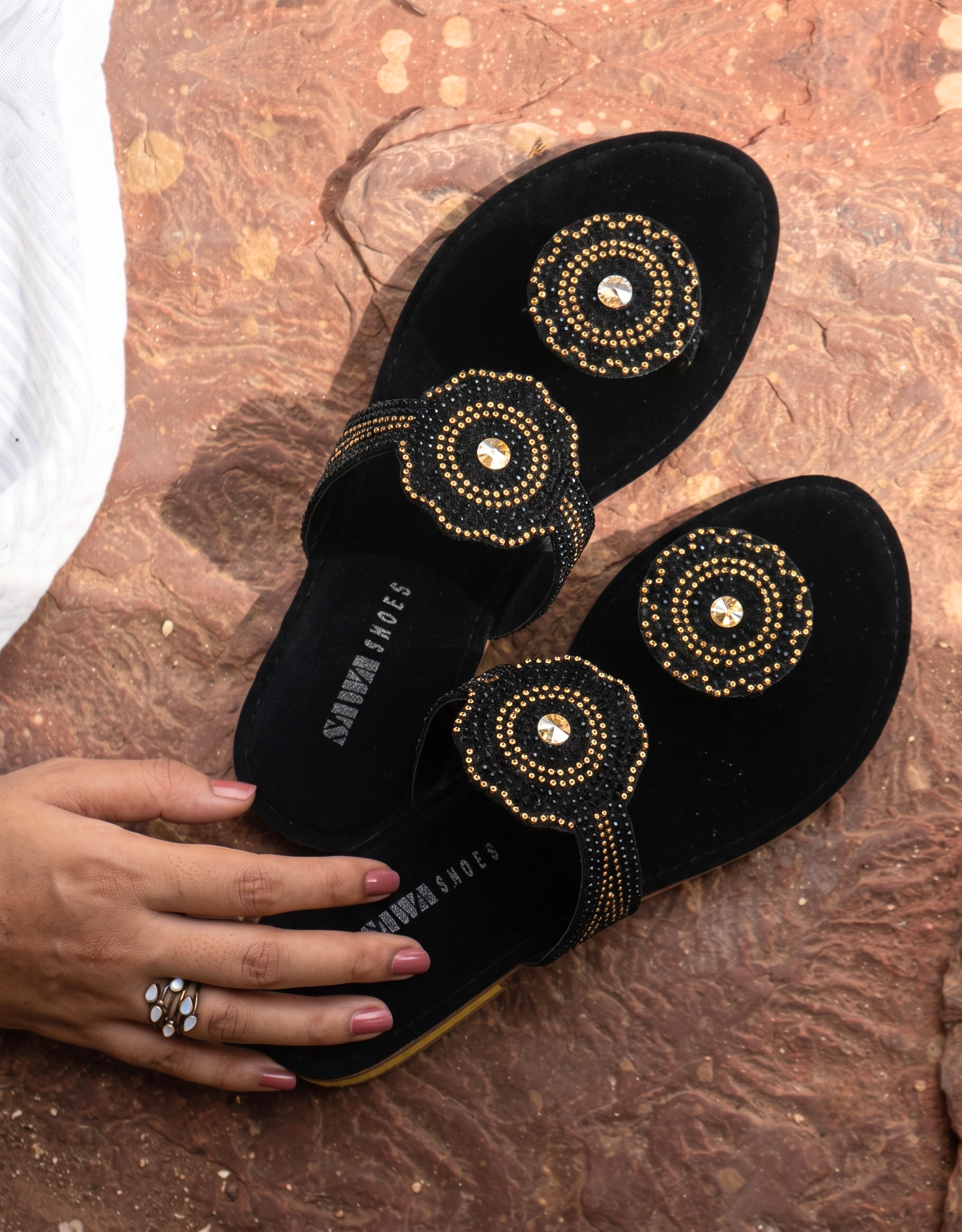 Black women’s flat slides with gold bead medallion design, crystal accents, toe-loop strap and low comfortable heel