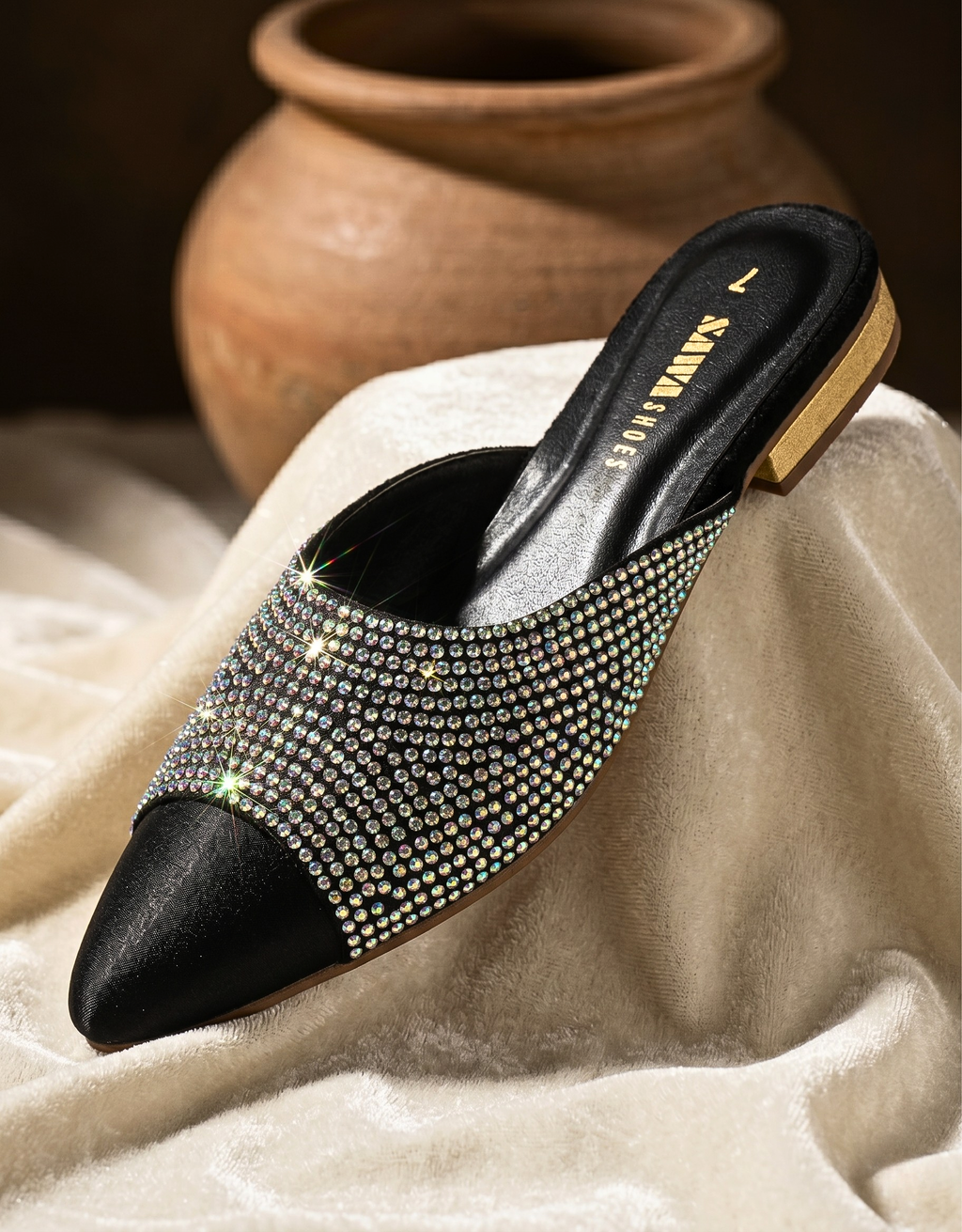 Black studded shoe on a textured surface with a blurred background