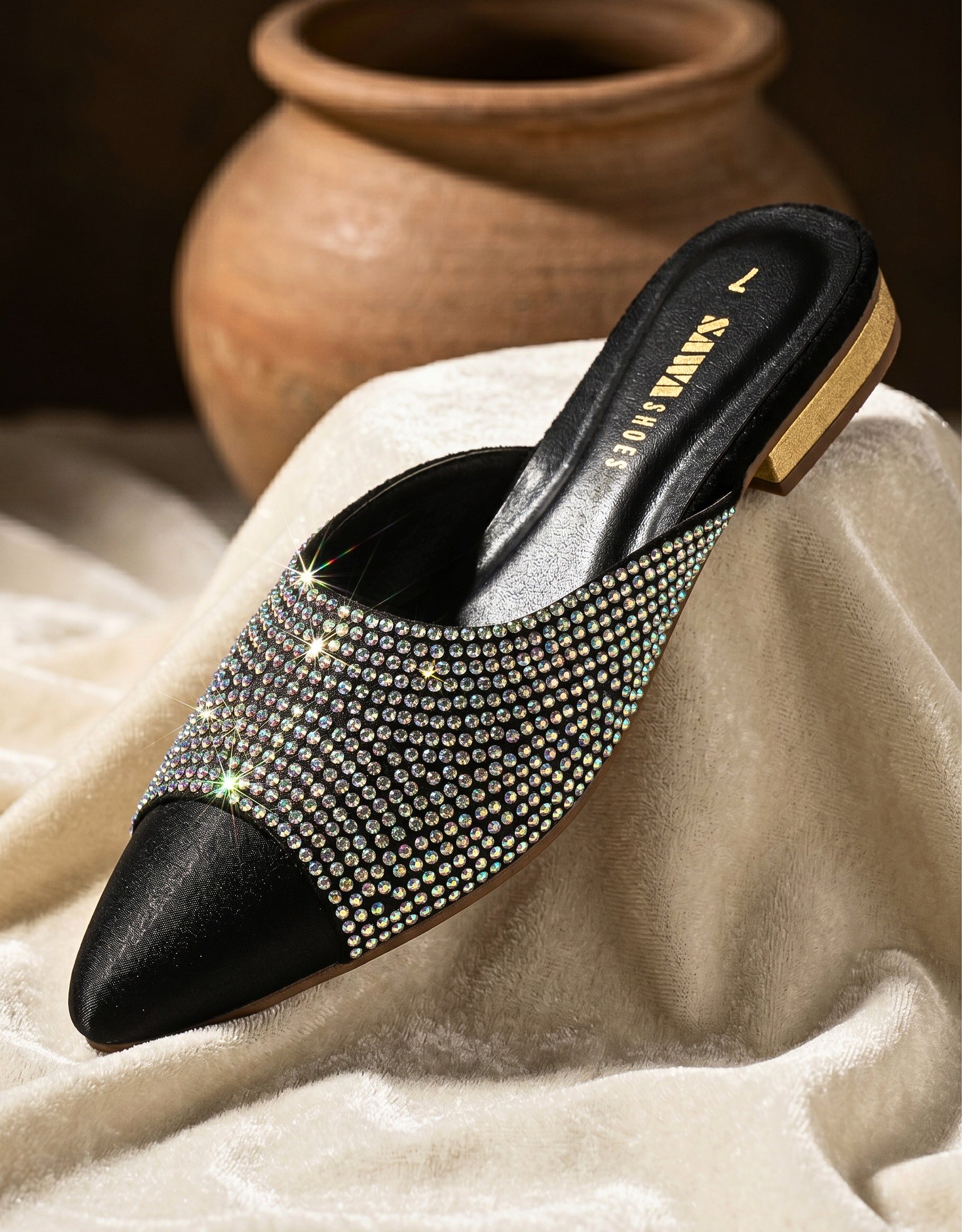 Black studded shoe on a textured surface with a blurred background