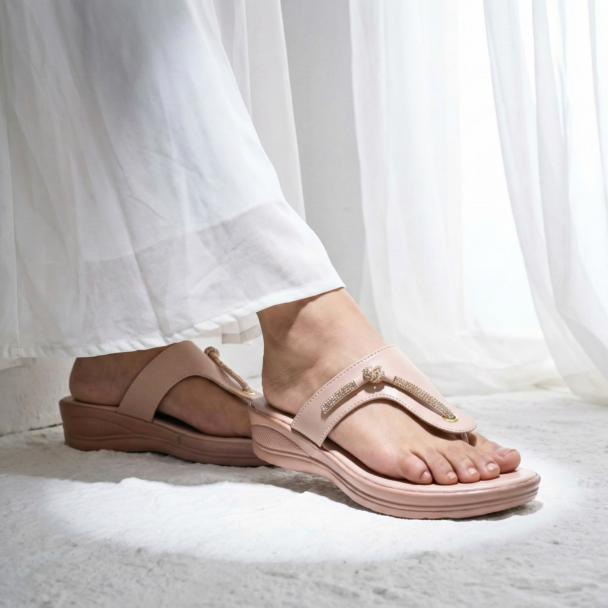 Side view of a woman wearing pink SAWA soft sole comfort chappals with rhinestone T-strap and gold heart detail