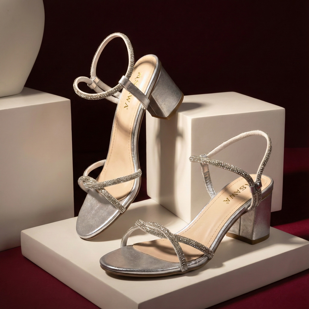 Silver high-heeled sandals on a white platform with a dark background