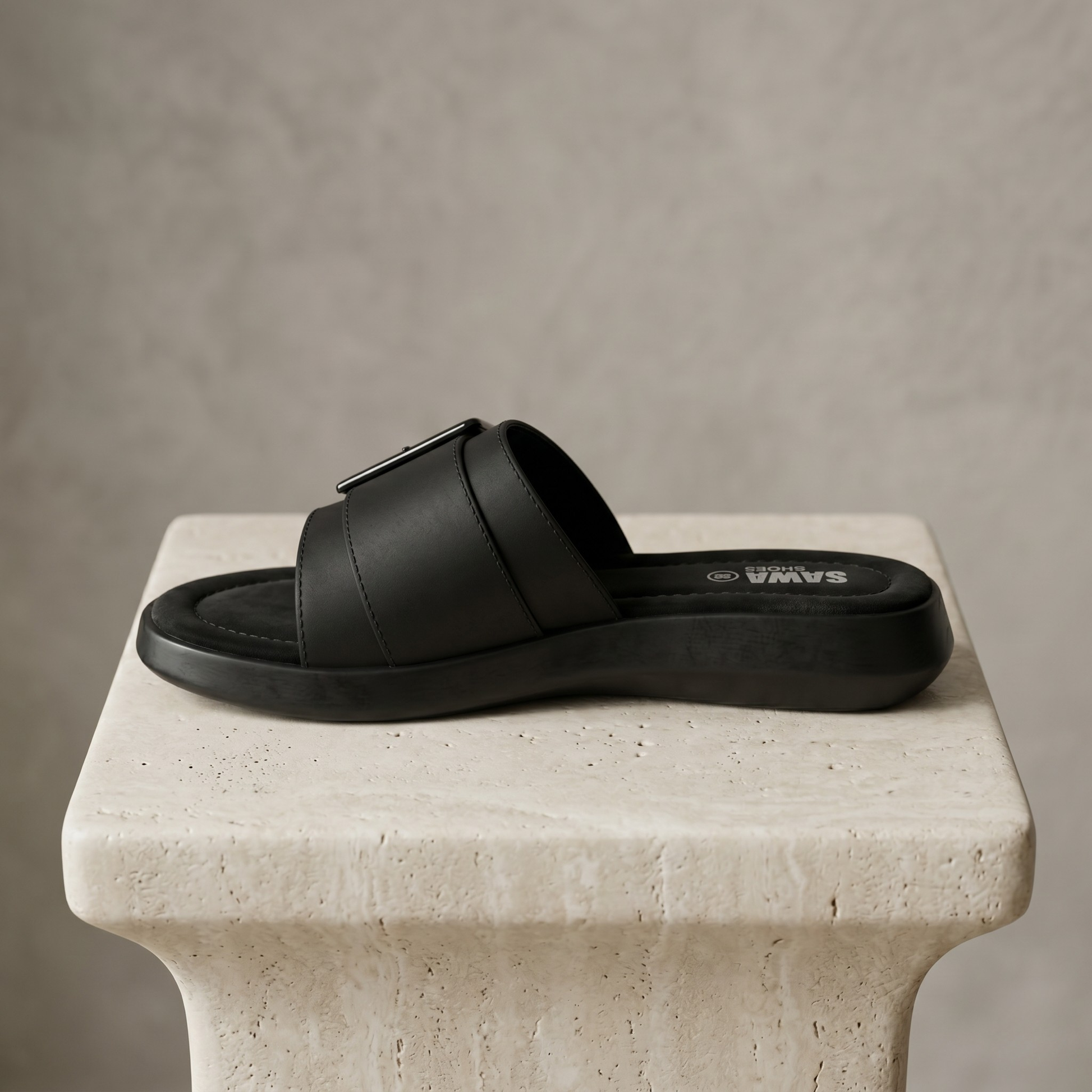 Black sandal on a stone pedestal with a neutral background
