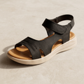 Black women’s comfort wedge sandals with a tan cushioned footbed, adjustable ankle strap and lightweight white 2.5-inch sole