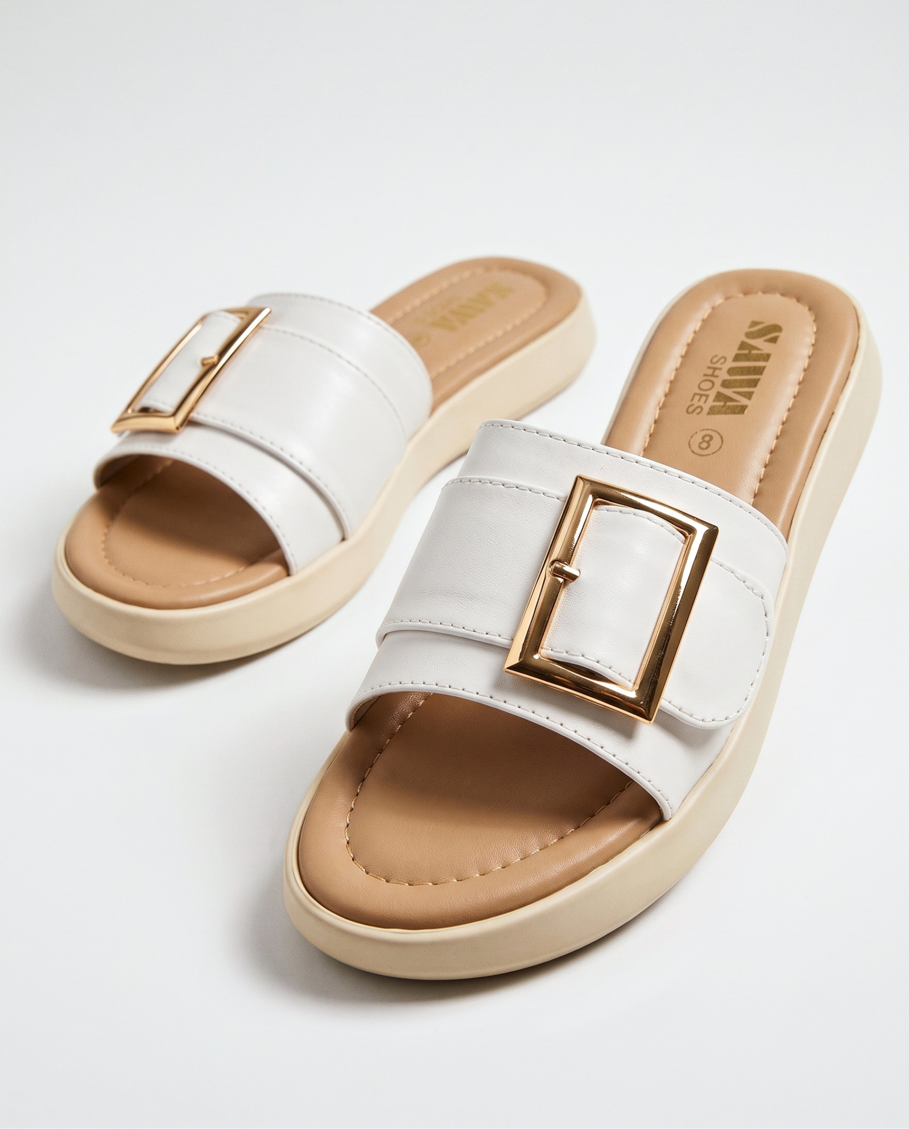 White slip-on platform slide sandal with a tan padded footbed and prominent gold buckle accent.