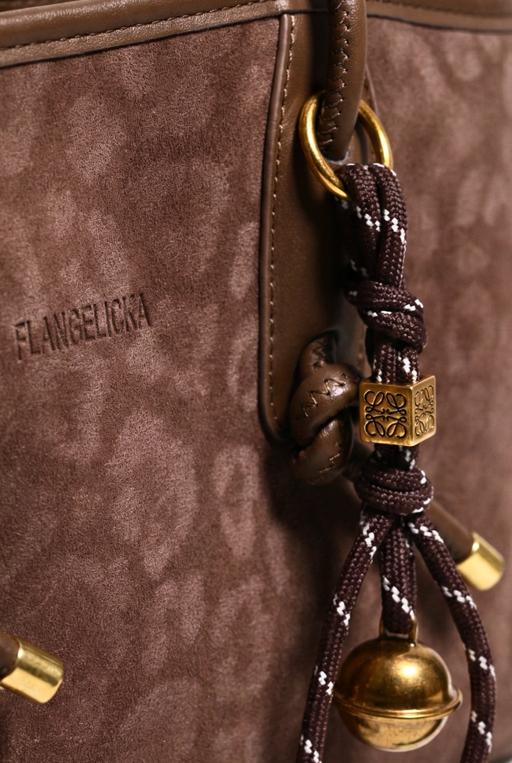 Close-up of a brown handbag with decorative elements and 'Flavie' branding.