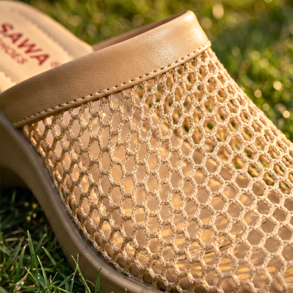 Close-up of a beige sandal with mesh design on grass