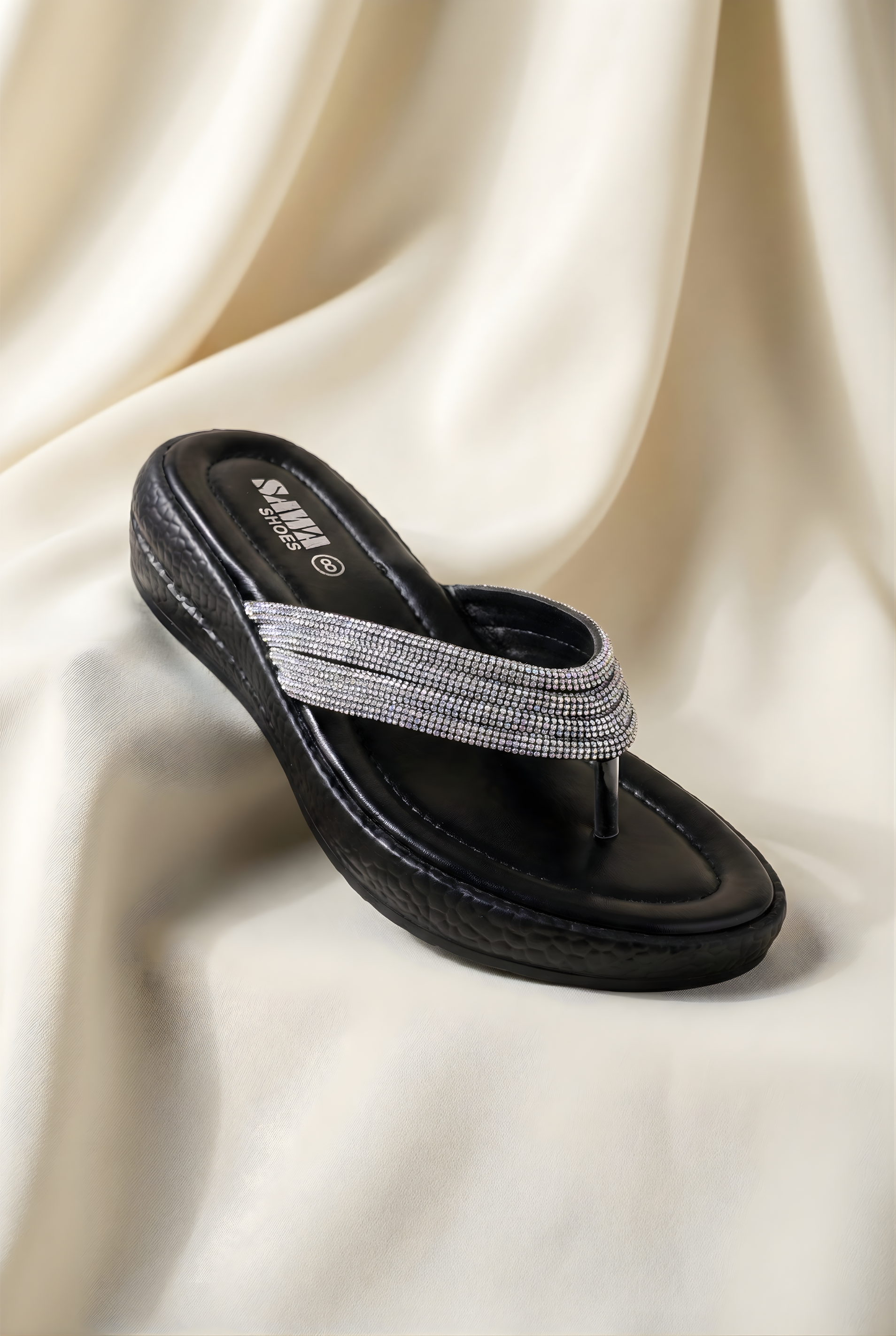 Black sandal with a gray strap on a beige fabric background