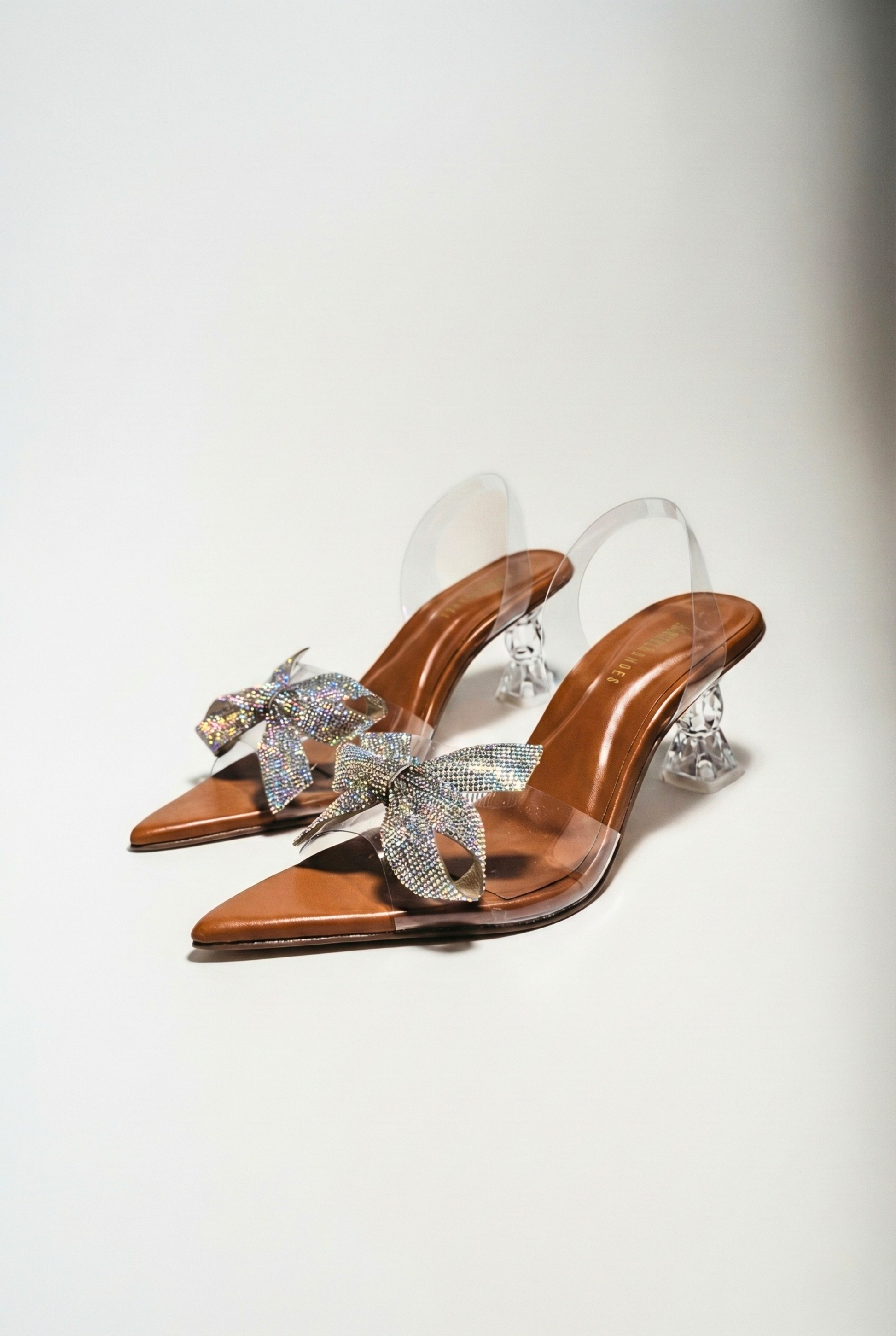 Side view of model wearing clear Cinderella heels showing architectural heel design and tan sole