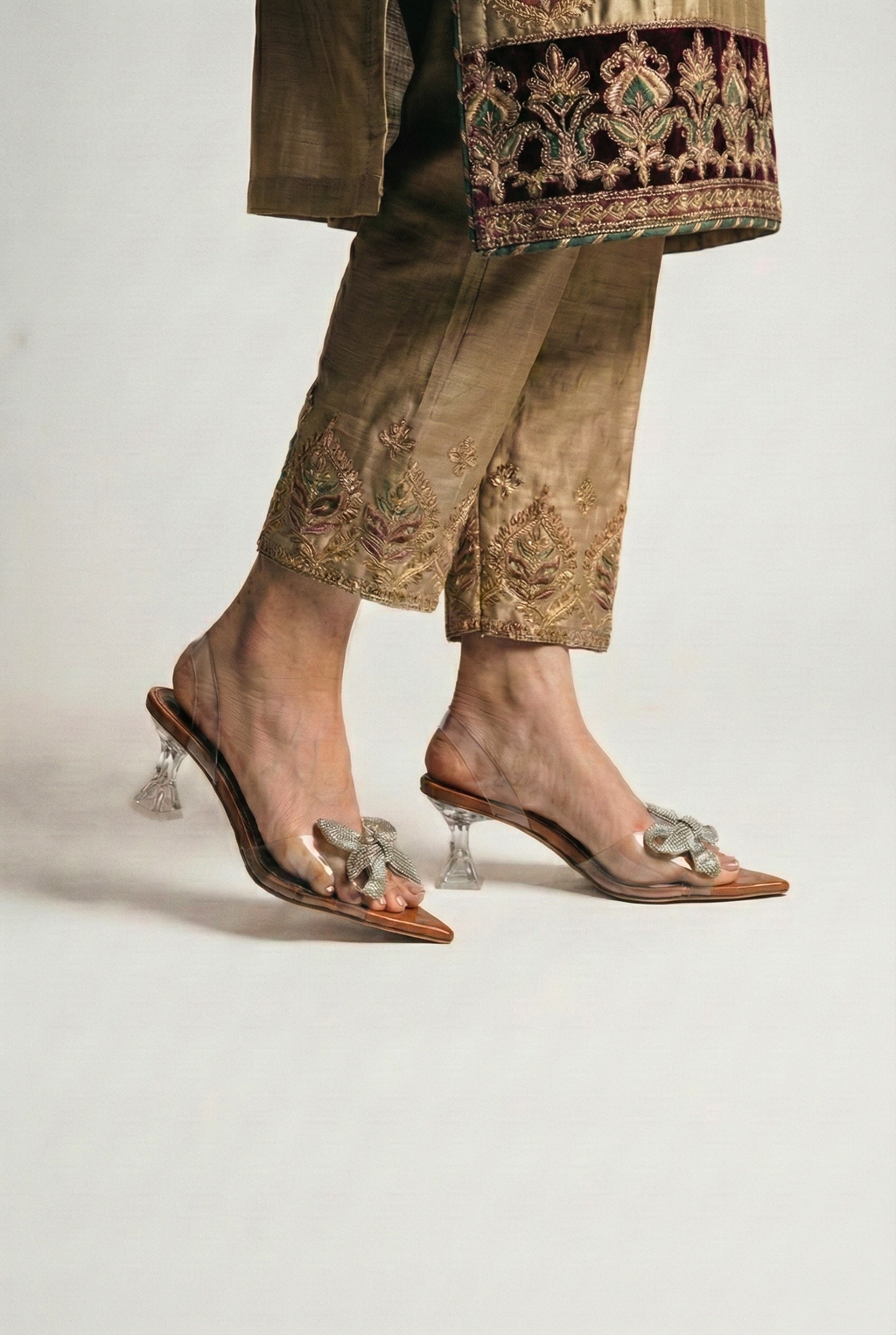 Side view of model wearing clear Cinderella heels showing architectural heel design and tan sole
