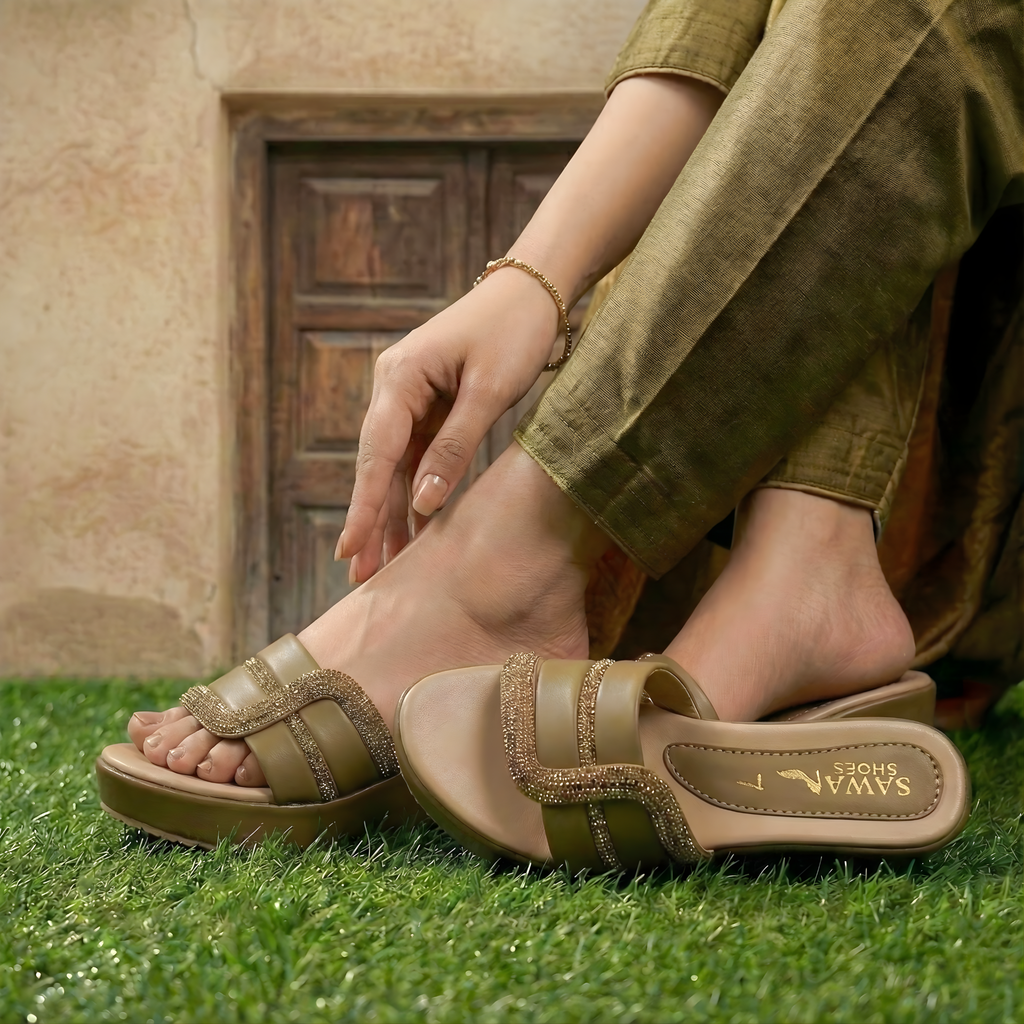 Person wearing brown sandals with shoe branding on grass