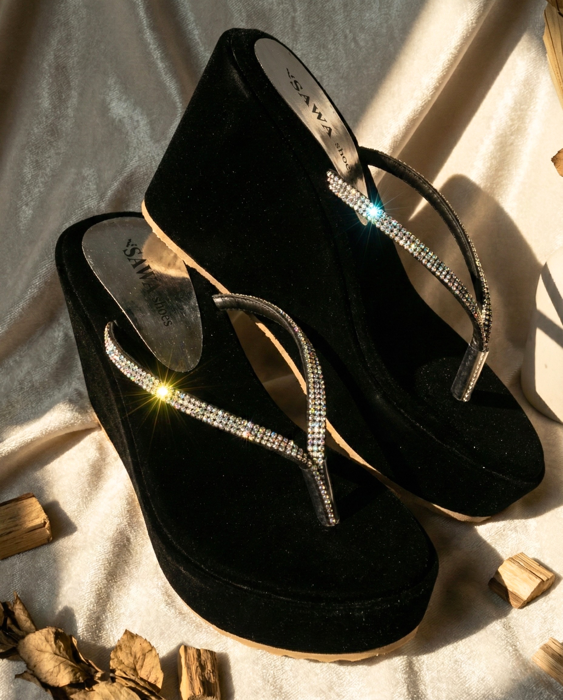 Black sandals with rhinestone straps on a textured surface