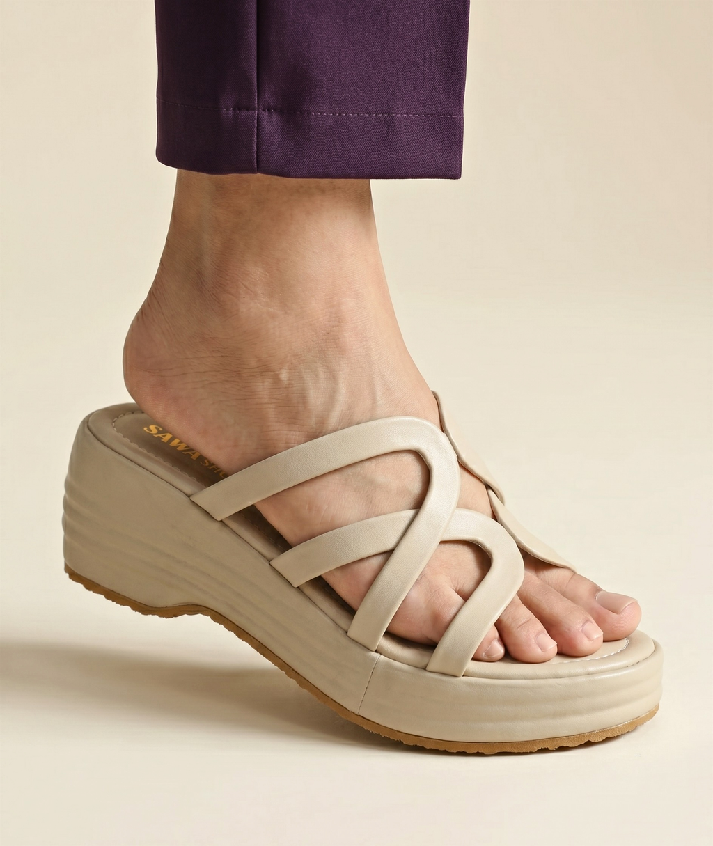 Side view of a person wearing a beige strappy platform wedge sandal paired with dark purple trousers