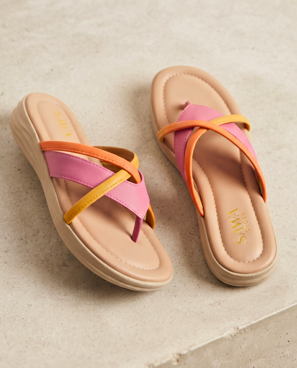 Pair of sandals with pink and orange straps on a textured surface