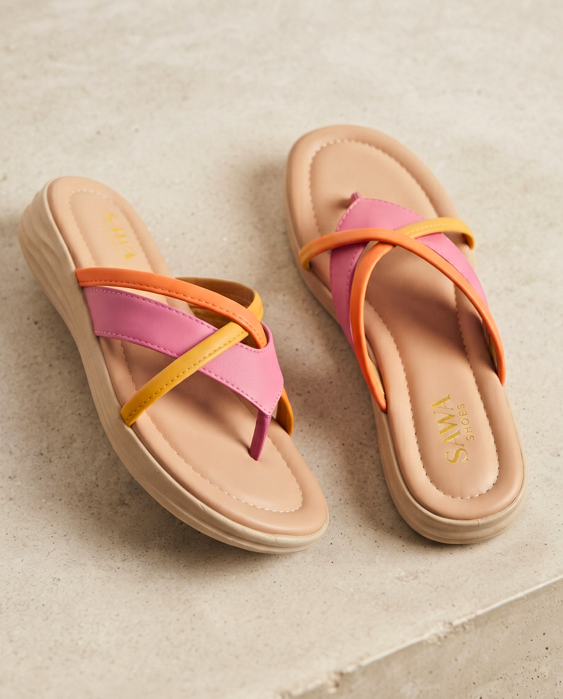 Pair of sandals with pink and orange straps on a textured surface