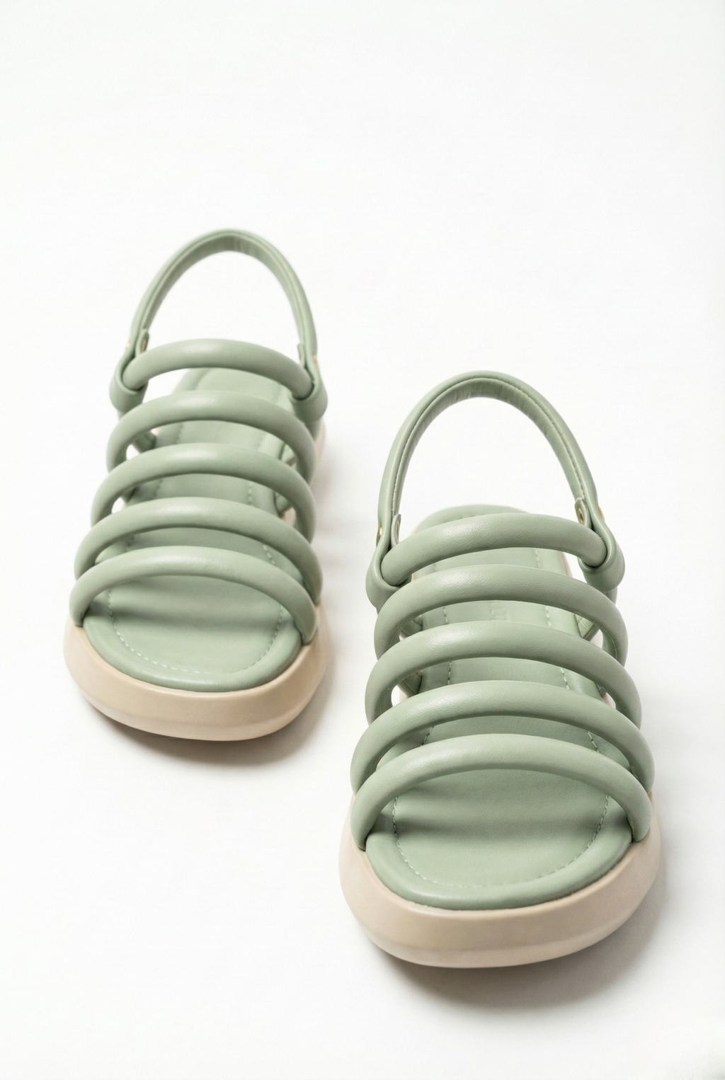 Pair of pistachio green padded gladiator sandals showing soft tubular straps and comfortable footbed.