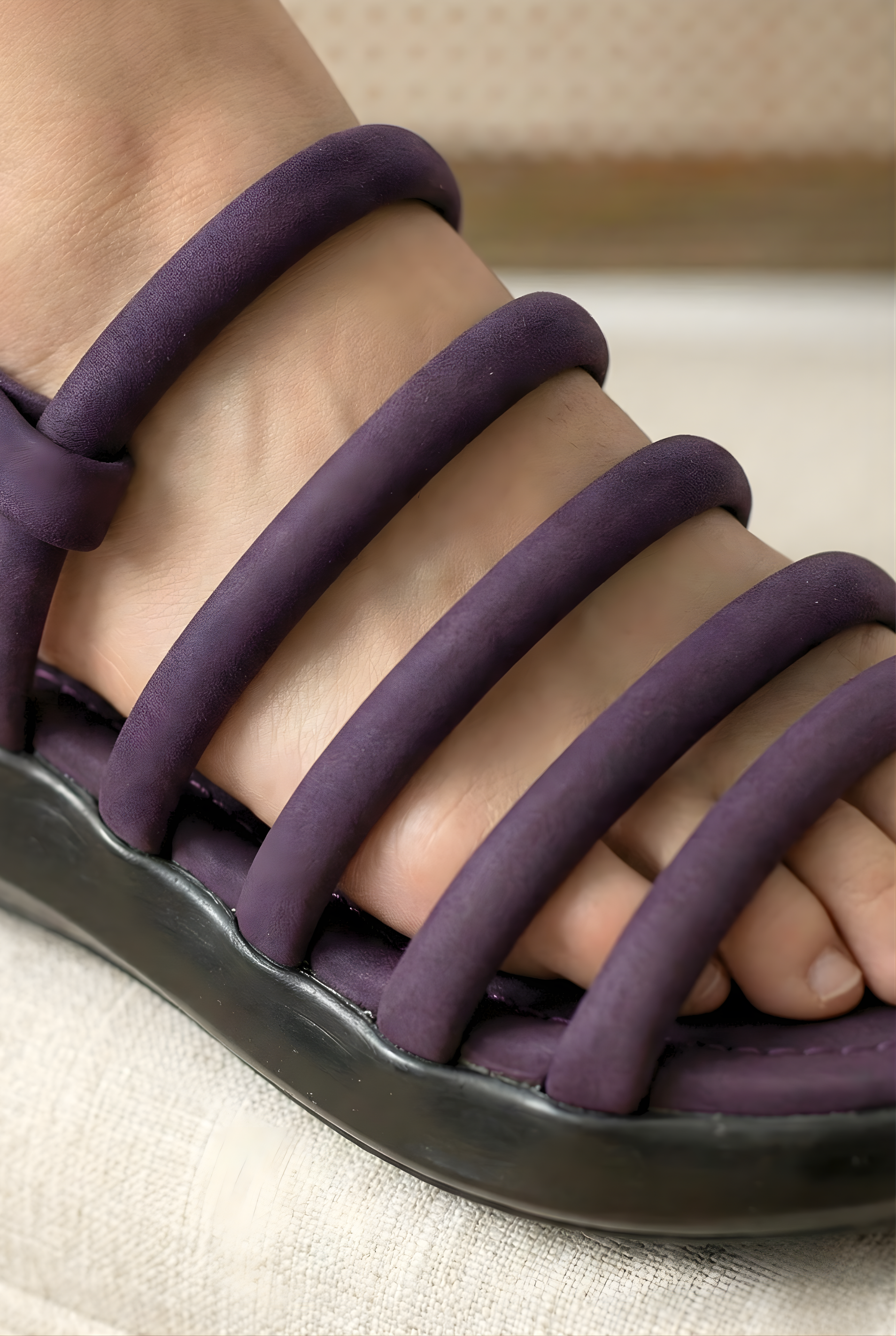 Close-up detail of purple puffy tube straps on ladies sandals with black flatform sole