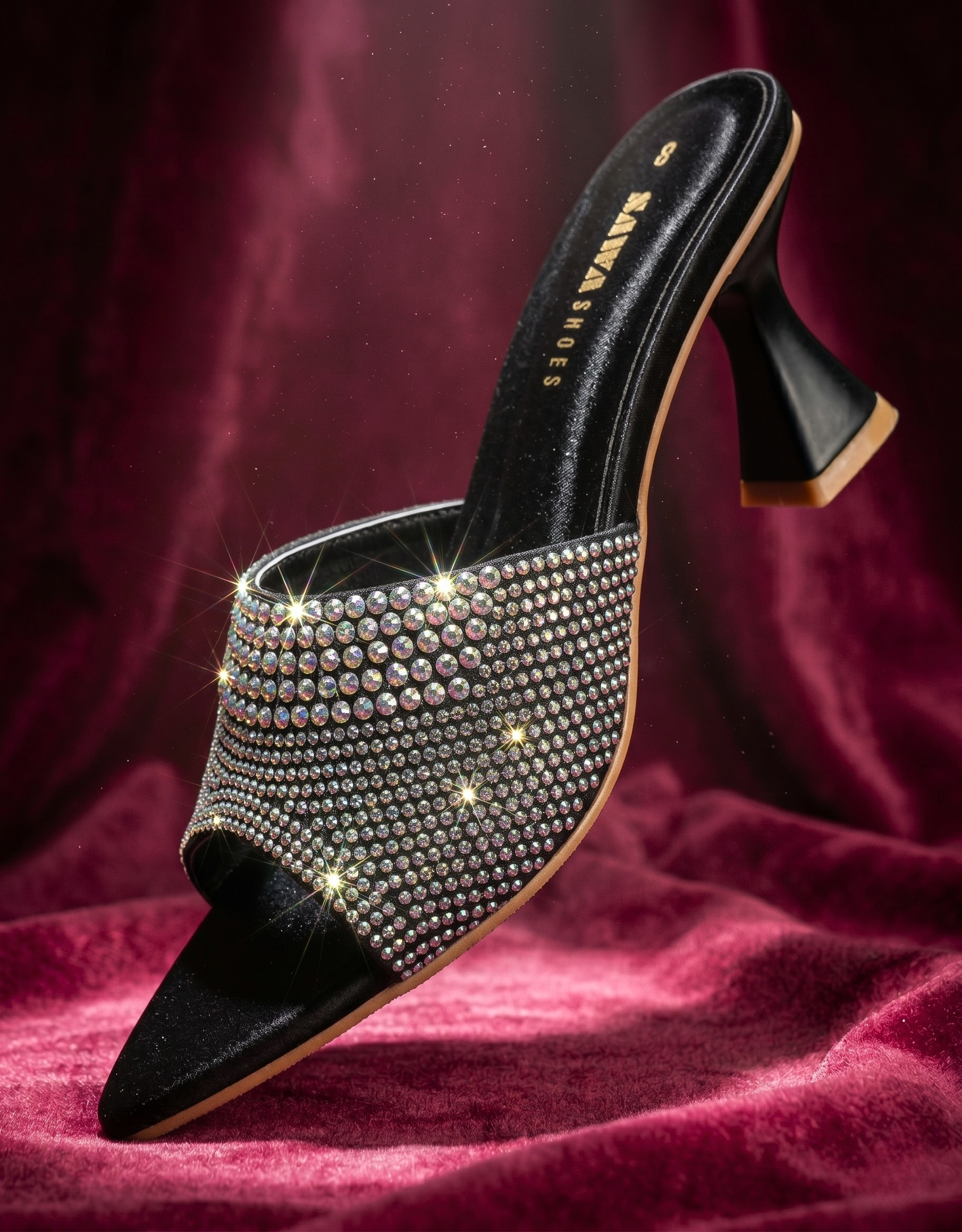 Black high-heeled shoe with crystal embellishments on a red fabric background