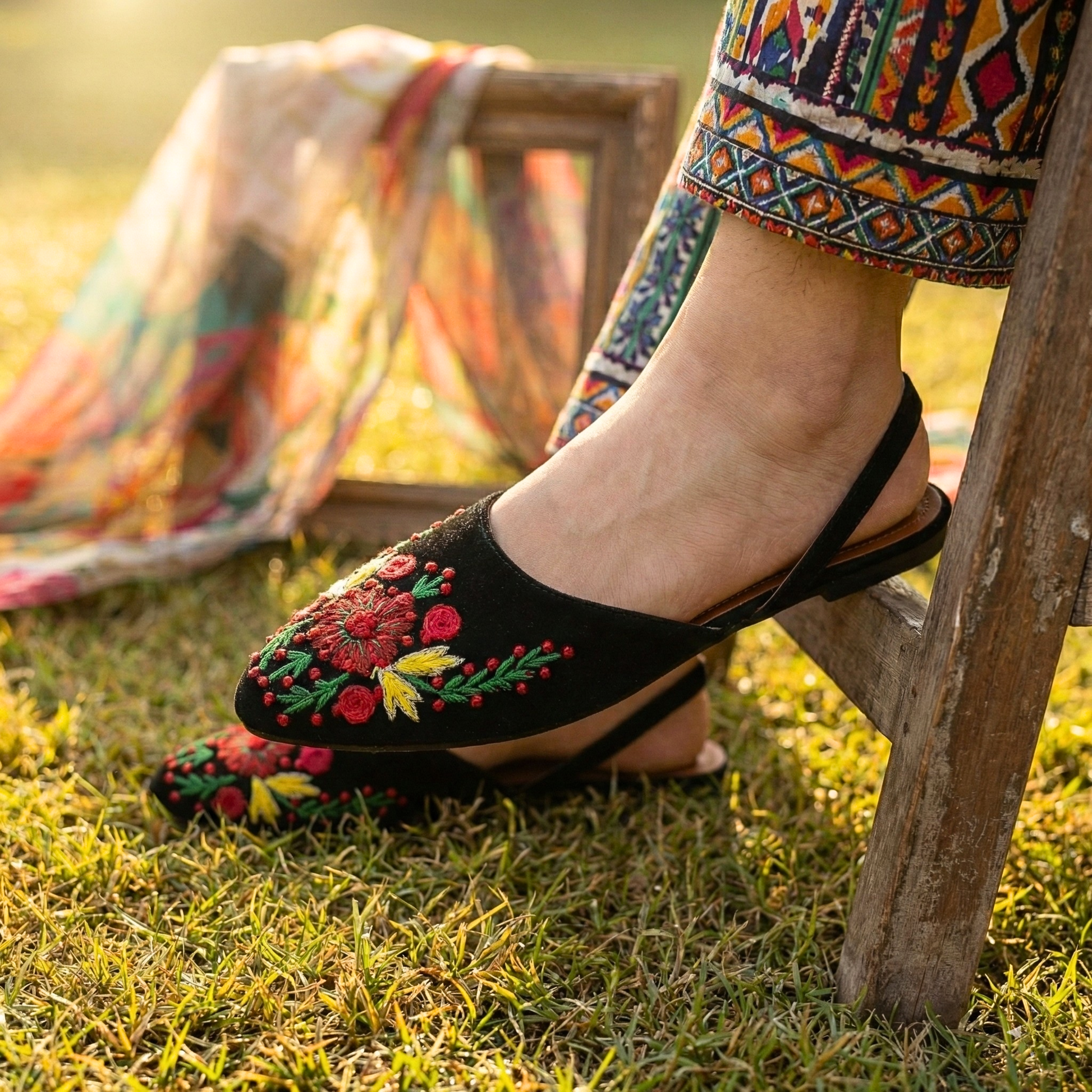 Sawa Shoes black slingback flats with red and yellow floral embroidery on a grass background