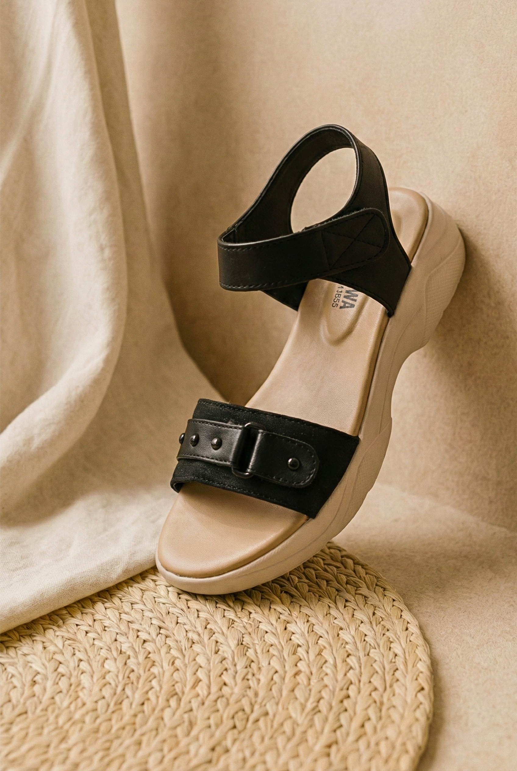 Side view of black comfort sandals with a thick beige contoured footbed and studded straps, priced at Rs. 2,390.
