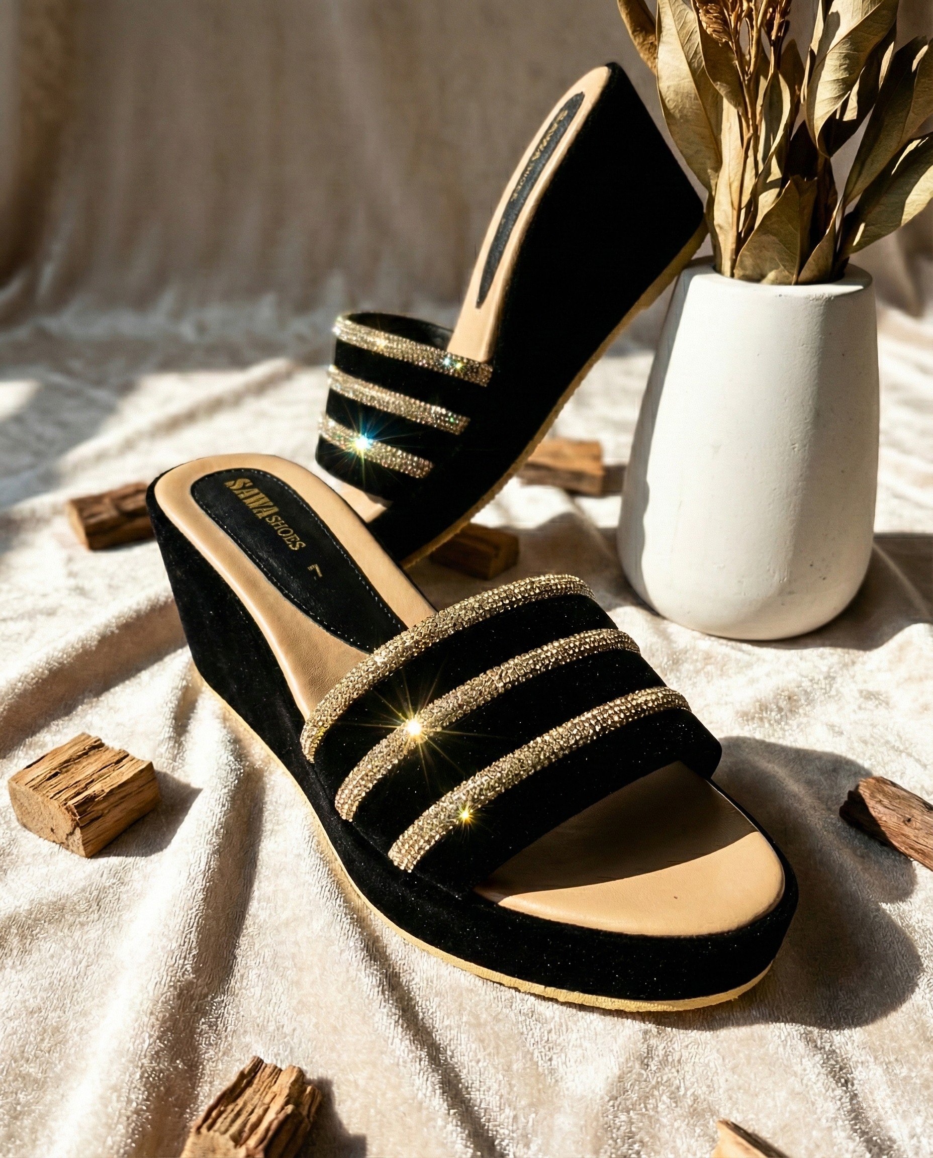 Top-down view of elegant black velvet slides with a tan cushioned footbed and shimmering party-wear details.