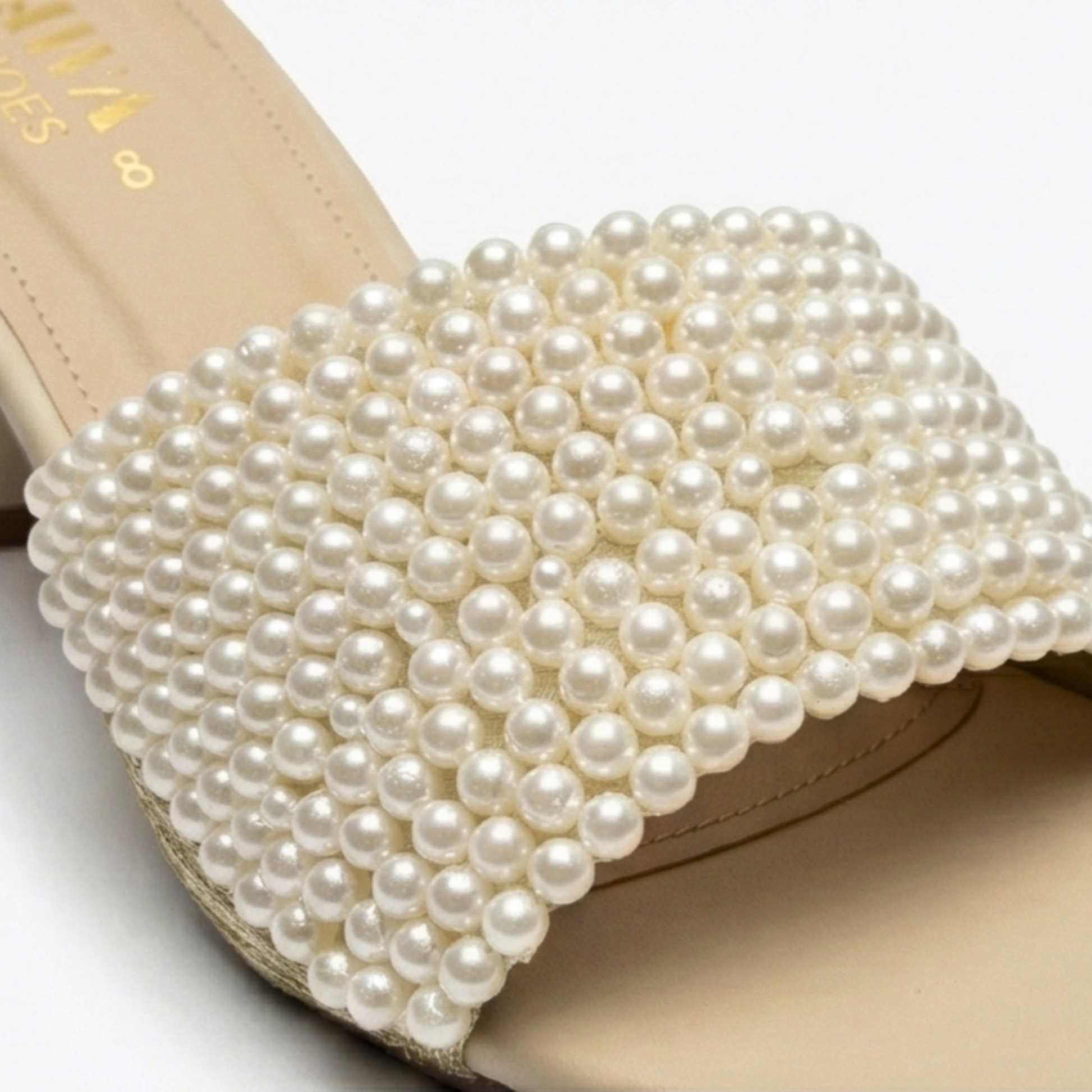 Close-up of elegant bridal mules in nude with high-luster pearl embellishments on a comfortable wide strap