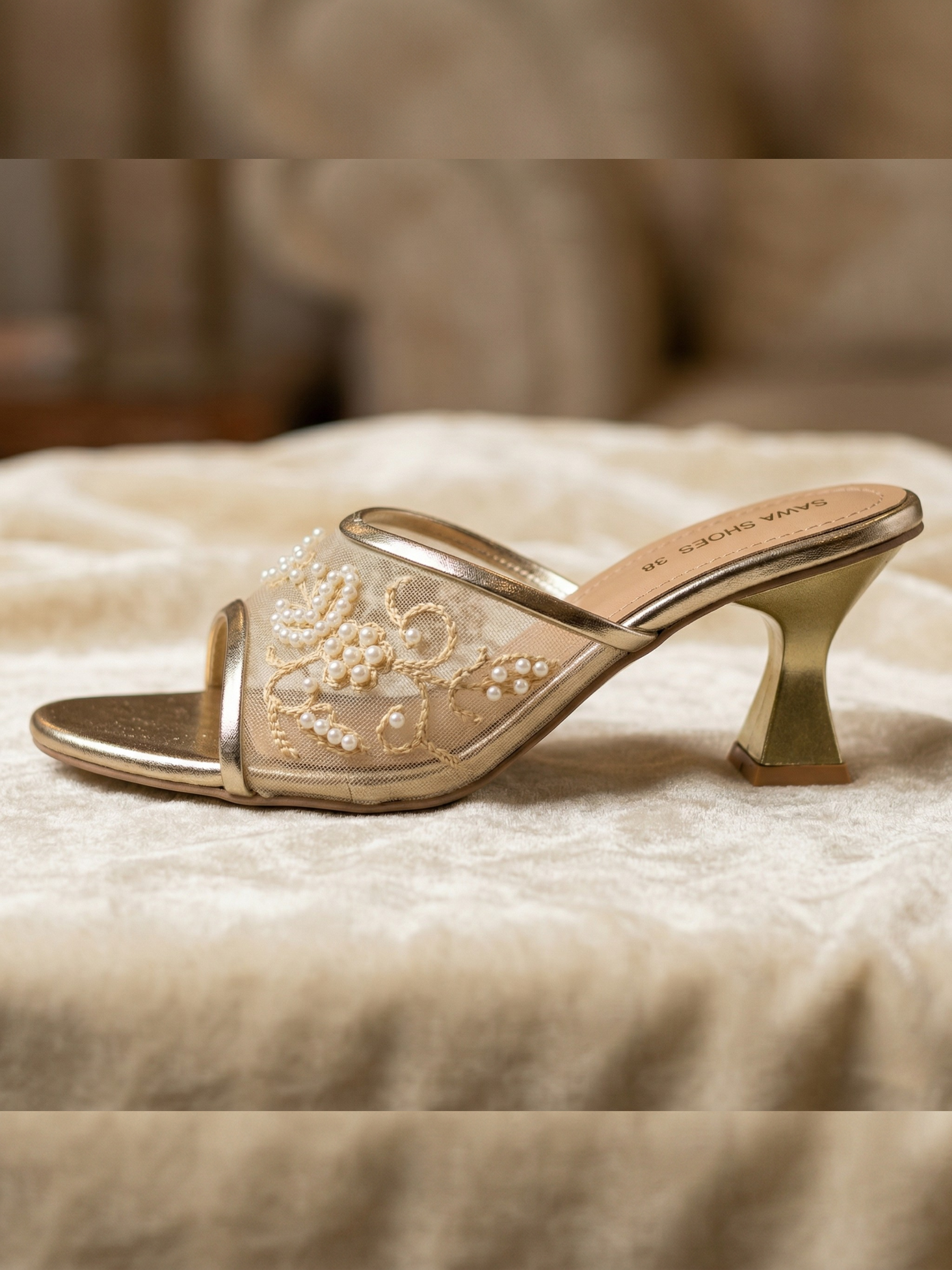 Single champagne gold heel showing the unique architectural heel design and pearl upper