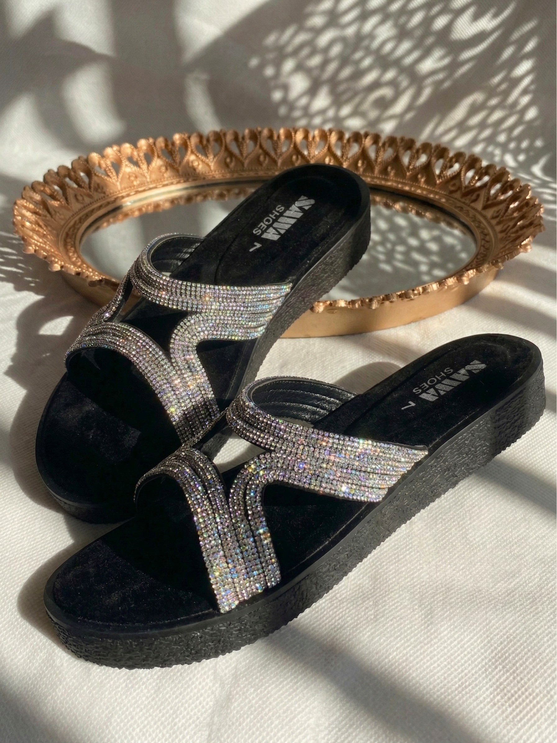 Pair of black sparkle slides with thick textured platform soles and shimmering crystals.