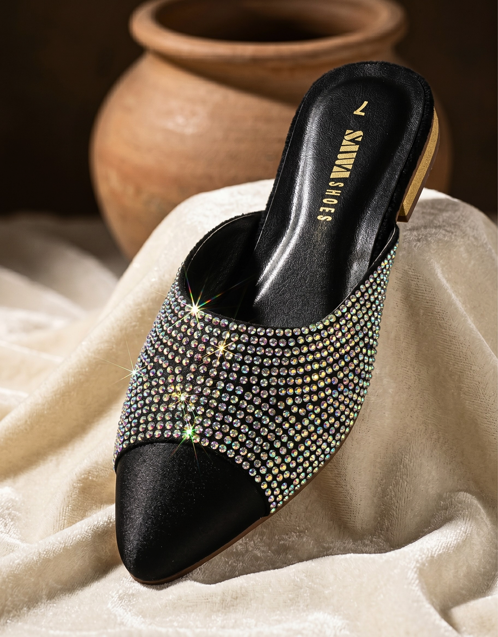 Black studded high-heeled shoe on a textured surface with a blurred background