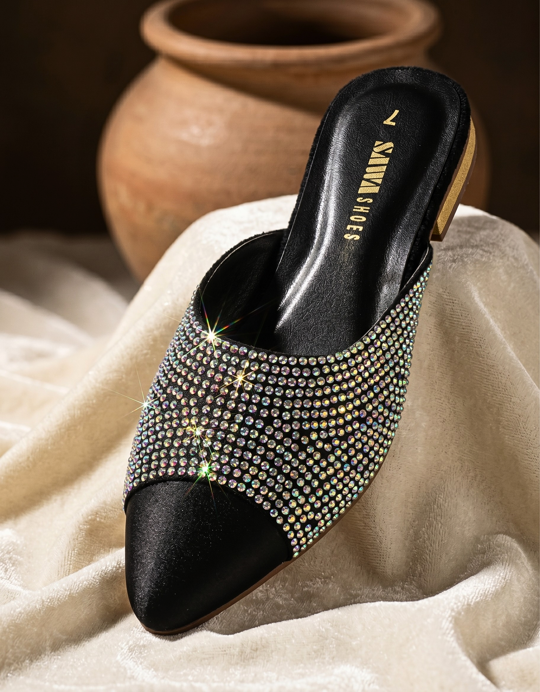 Black studded high-heeled shoe on a textured surface with a blurred background