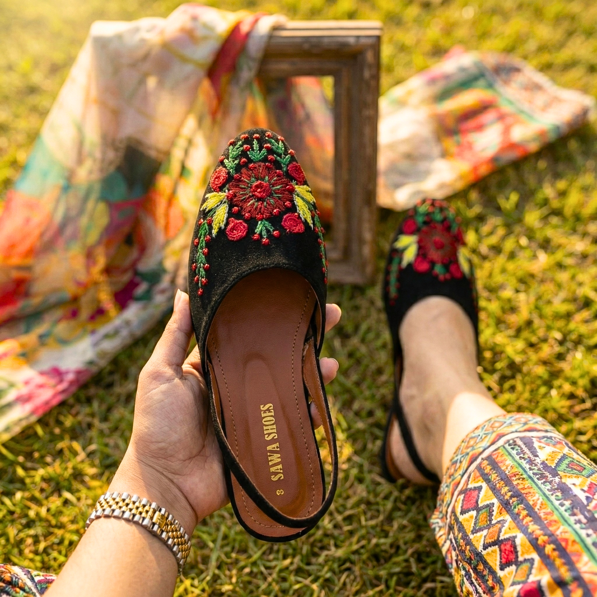 Sawa Shoes black slingback flats with red and yellow floral embroidery on a grass background
