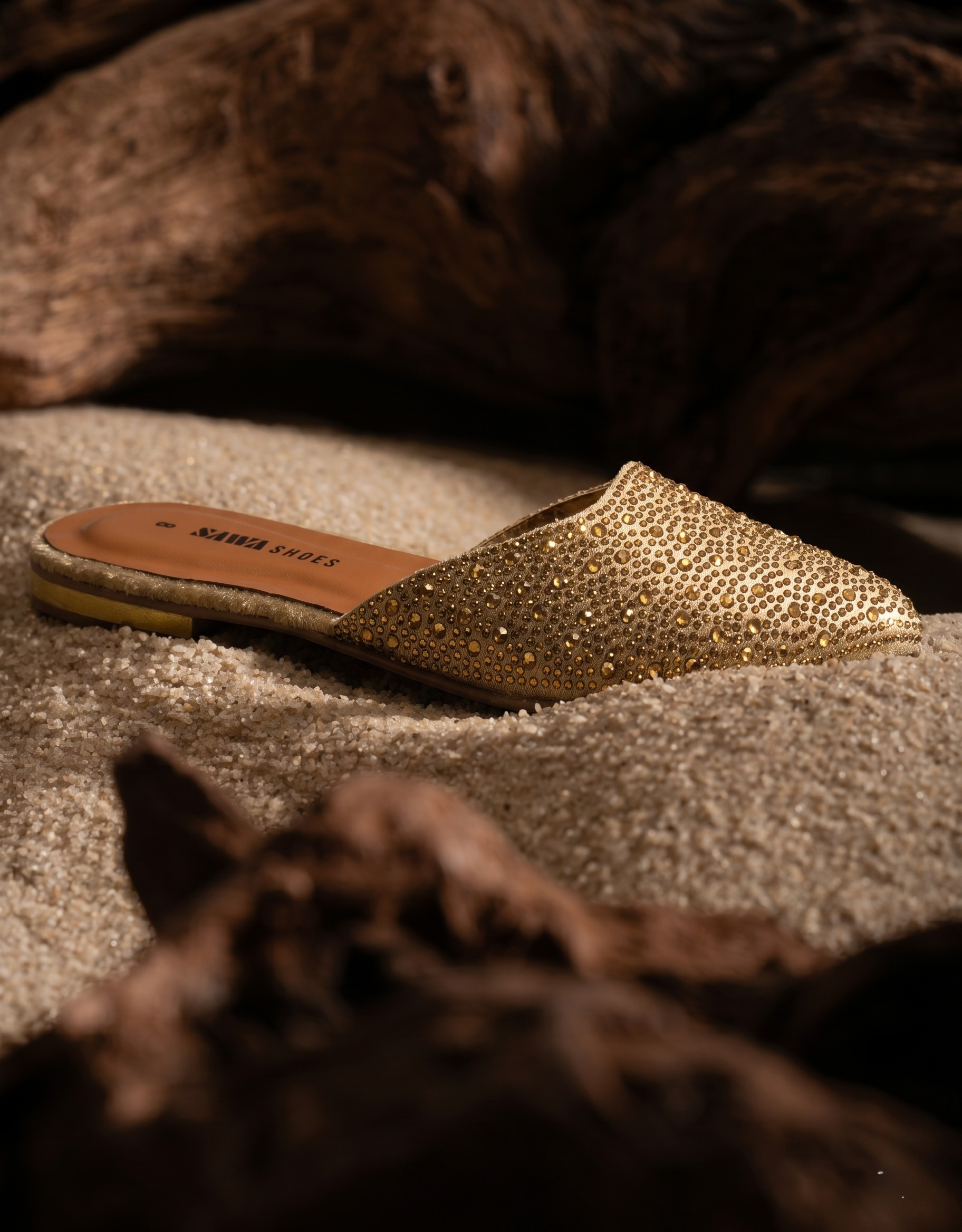 Gold slipper with rhinestone embellishments on a textured surface