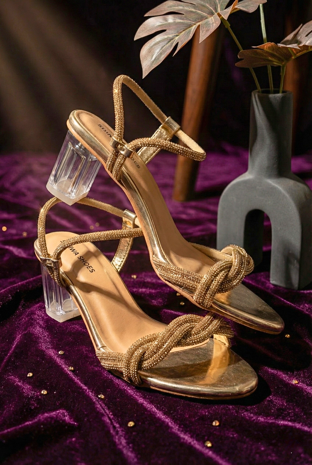 Gold braided rhinestone heels with clear glass block heel on purple velvet background.