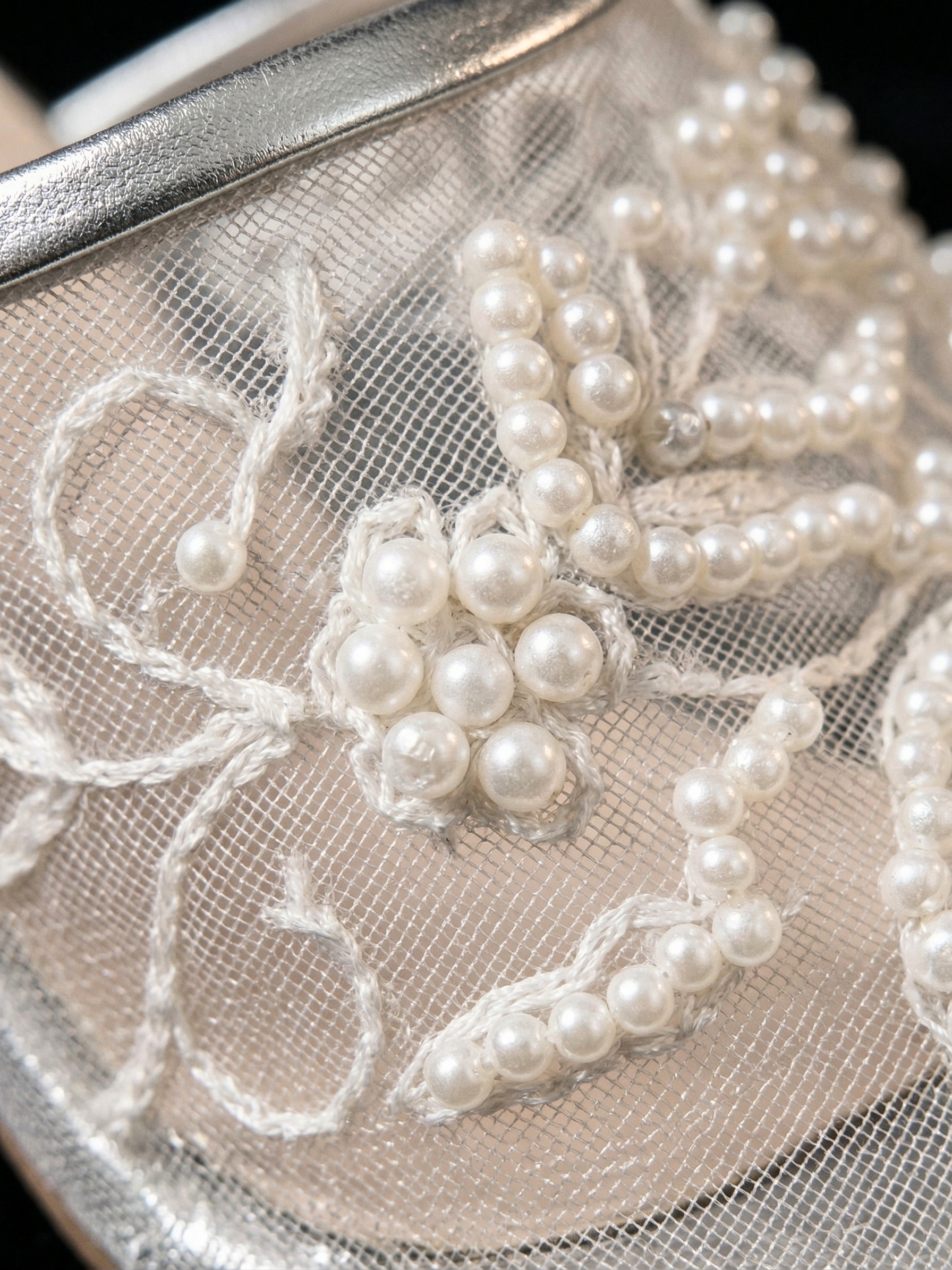 Detail shot of 3D pearl floral embroidery on transparent silver mesh bridal mules