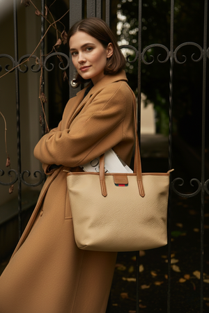 Woman wearing a camel-colored wool coat carrying the Oxford tote bag over her shoulder