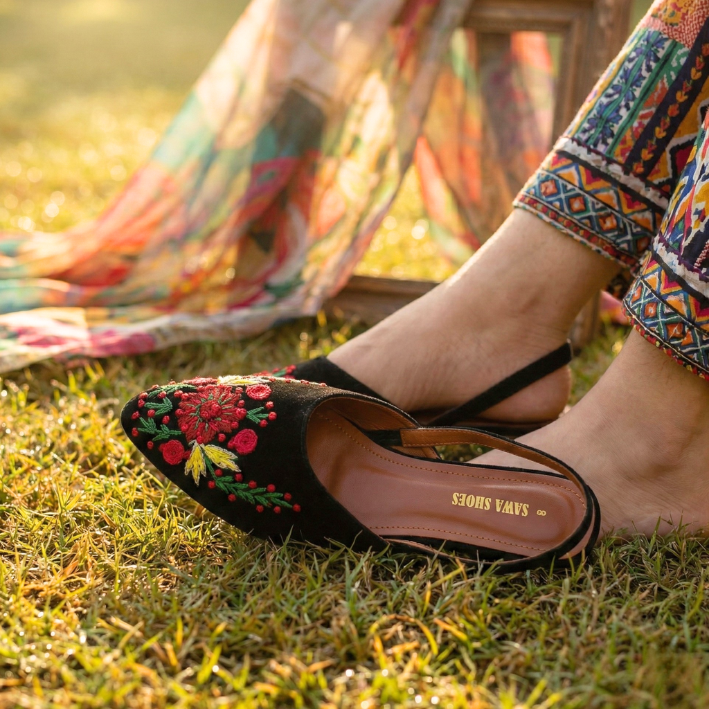 Woman wearing Sawa Shoes embroidered black slingback khussas with a traditional printed Pakistani suit.