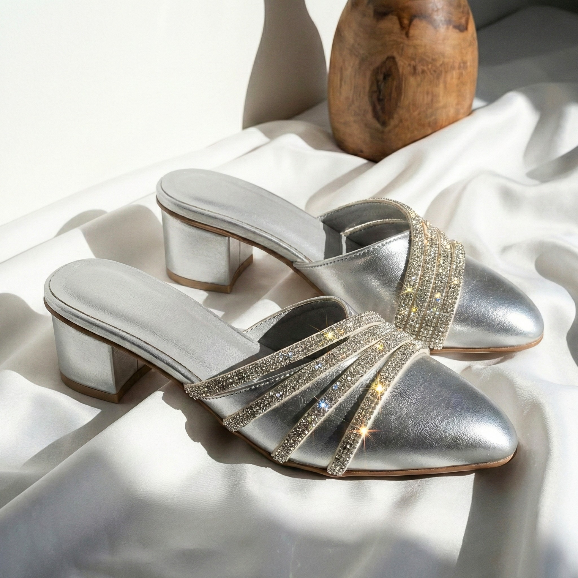 Close-up of shimmering rhinestone straps on silver metallic mules for party wear