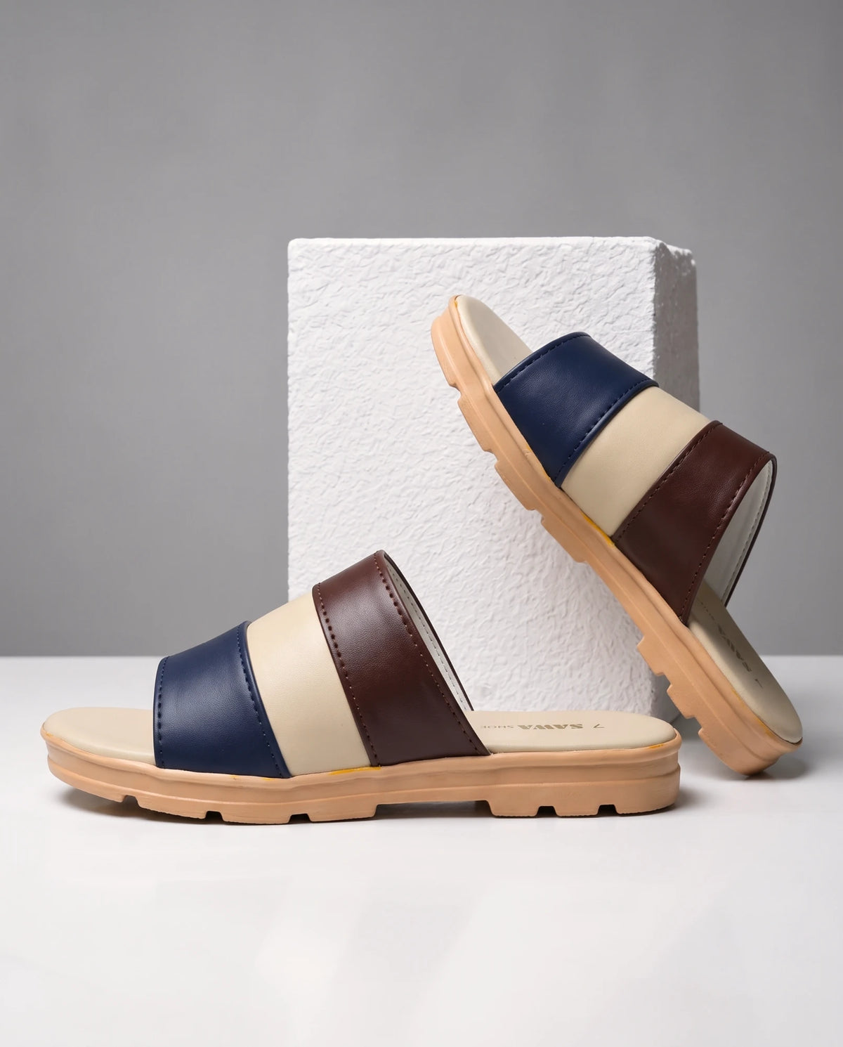 Pair of navy, cream and brown casual slides with tan grip sole