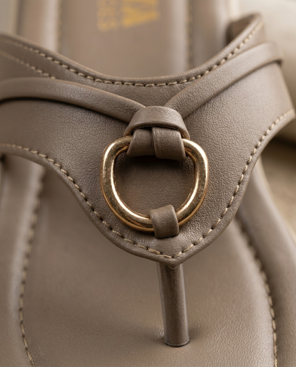 Close-up of a gray sandal with a gold ring buckle.