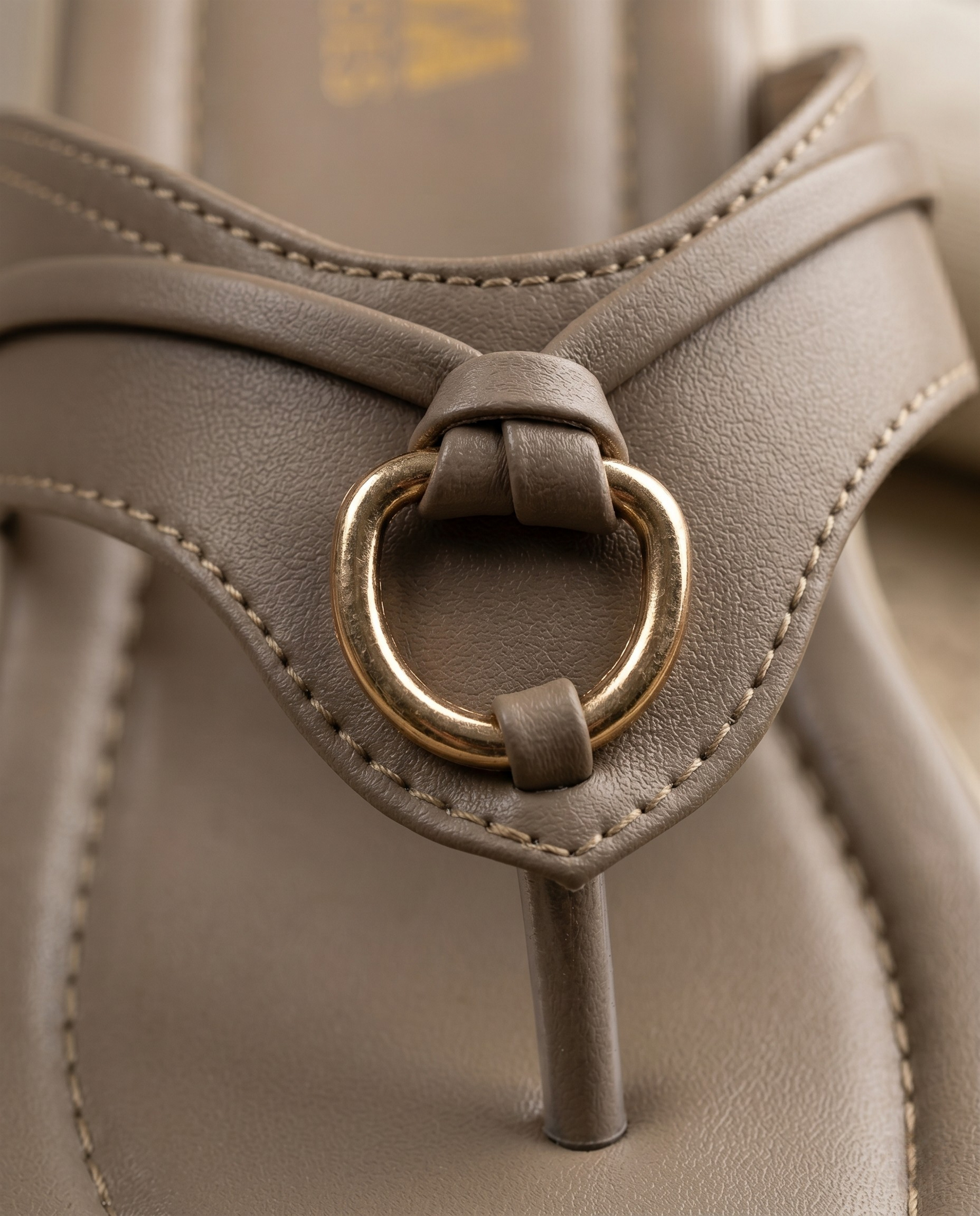 Close-up of a gray sandal with a gold ring buckle.