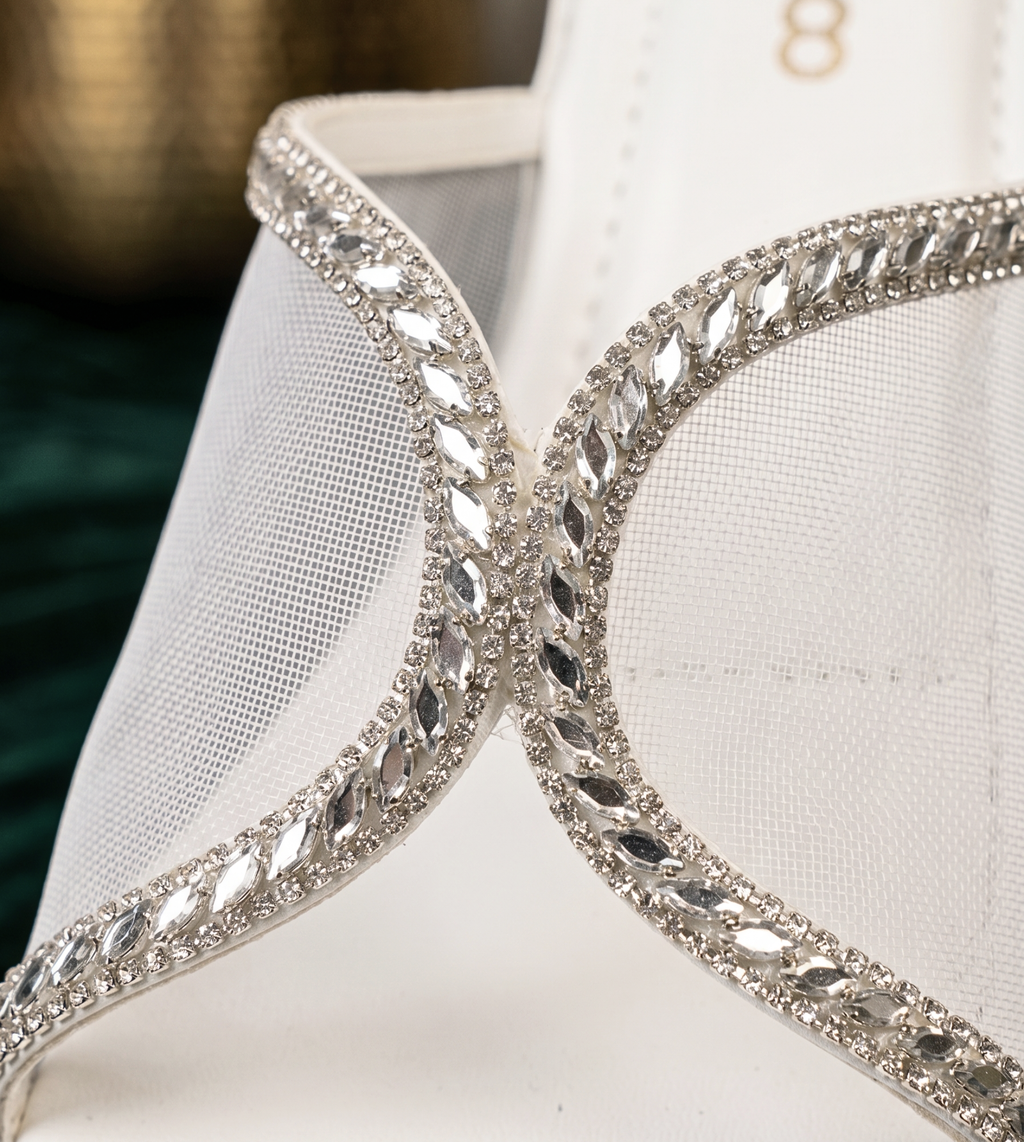 Close-up of white mesh sandal strap featuring intricate silver rhinestone crystal borders and marquise-cut gems