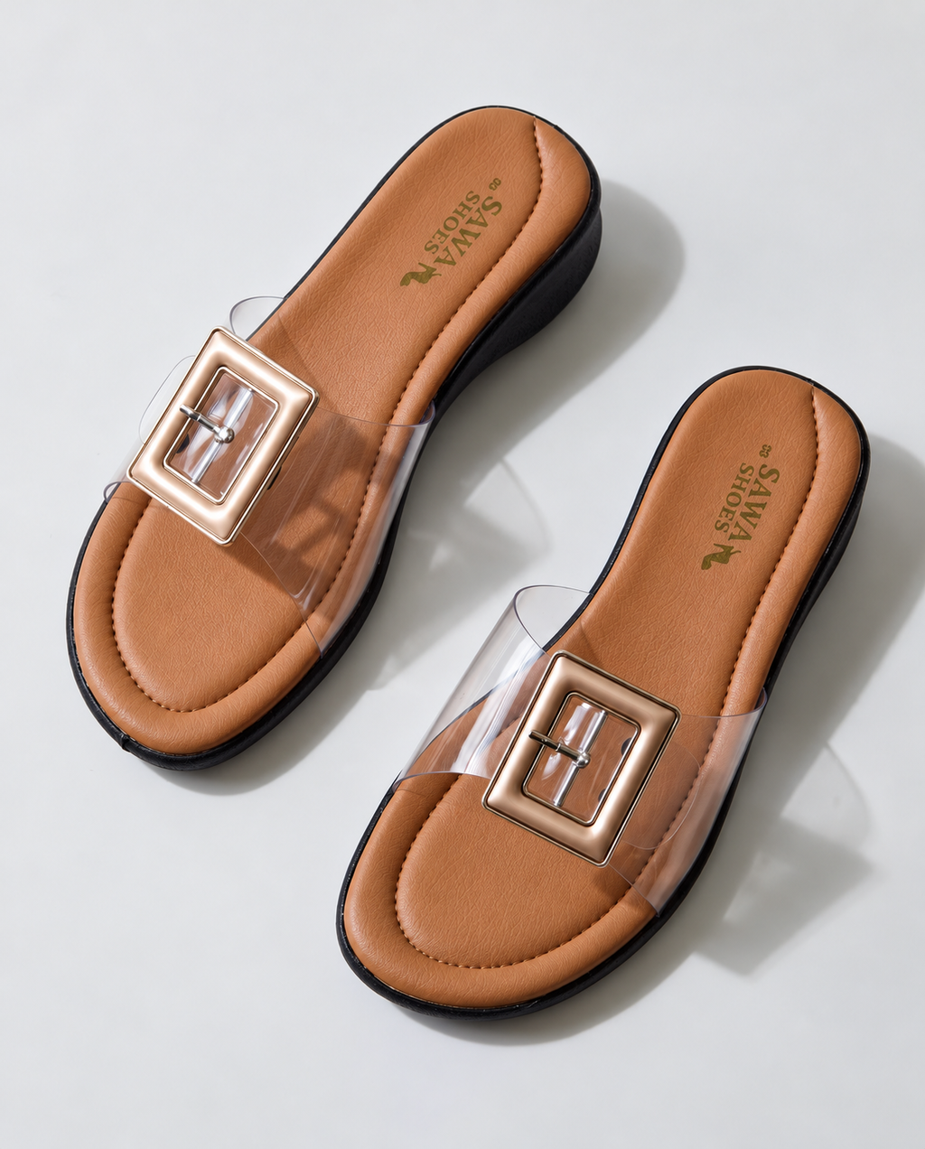 Pair of ladies clear buckle wedge slippers with black sole, angled view