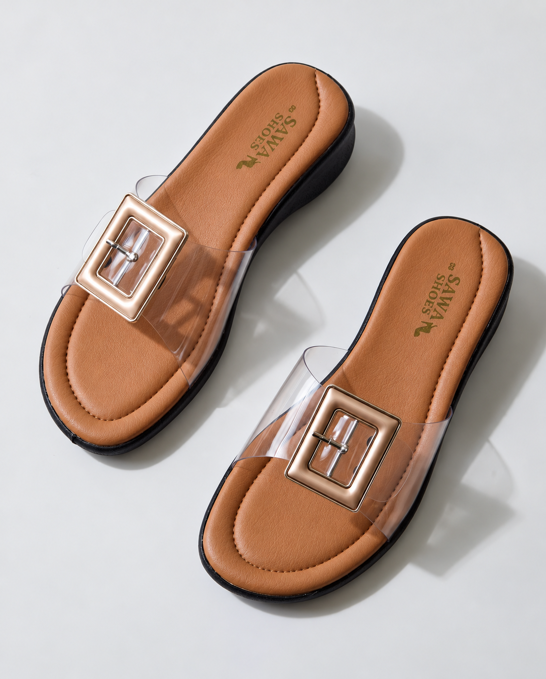 Pair of ladies clear buckle wedge slippers with black sole, angled view